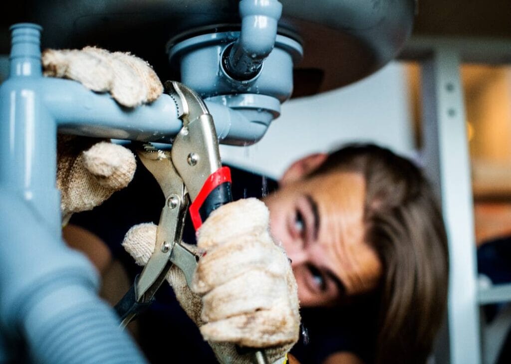 Professional plumber repairing a leaking kitchen sink drain, one of the common plumbing problems in Midland TX, providing expert residential plumbing repair services.