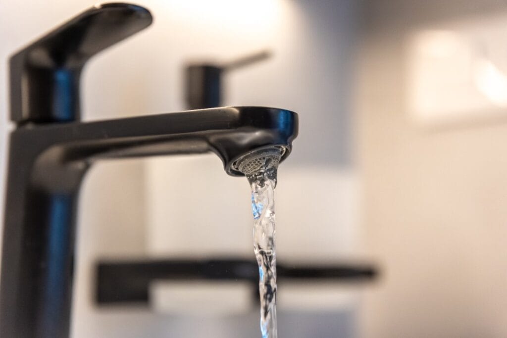 Close-up of a modern black bathroom faucet with low water flow, representing a low water pressure problem in Midland, Texas.